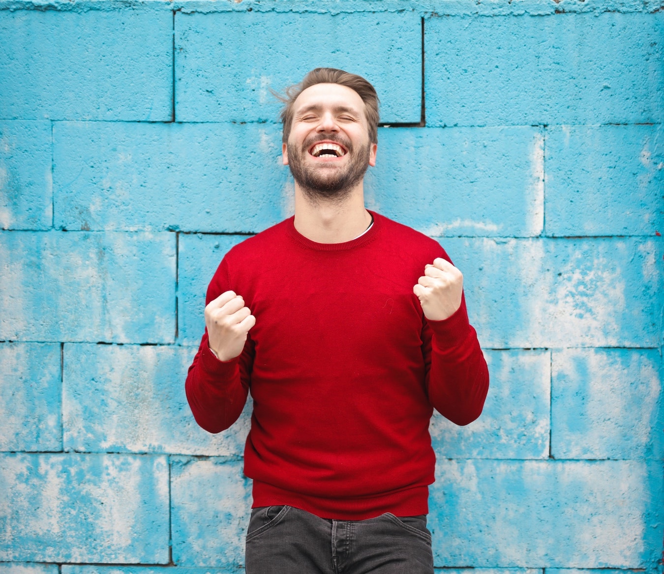 junger Mann im roten Pullover lächelt selbstsicher und selbstbewusst