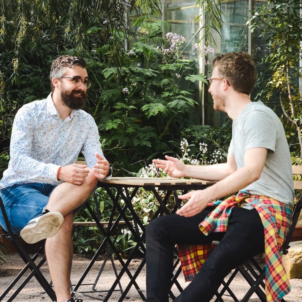 zwei junge Männer sitzten in einem Café an einem Tisch und unterhalten sich