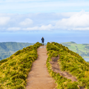 Selbstsabotage überwinden: junger Mann steht auf einem Hügel und genießt