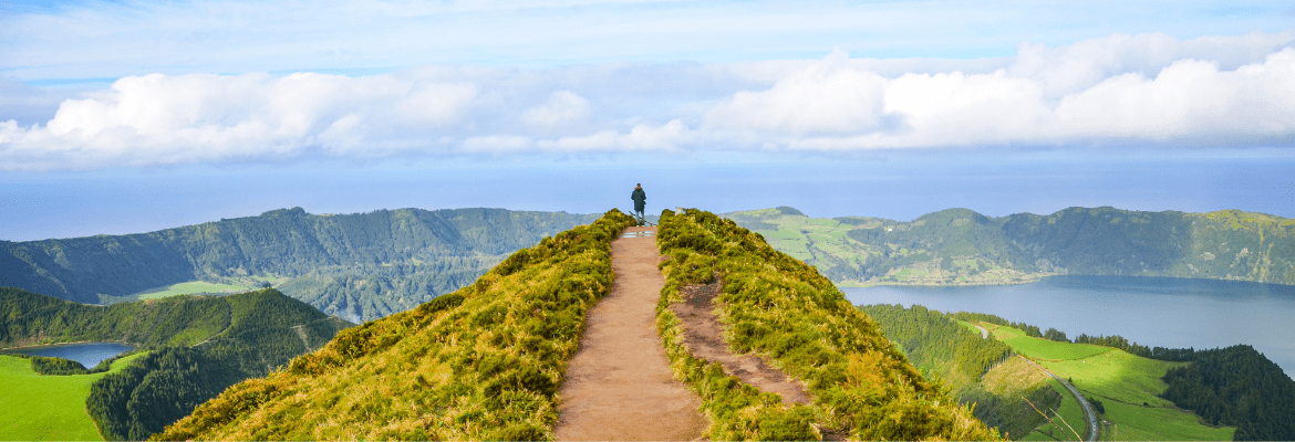 Selbstsabotage überwinden: junger Mann steht auf einem Hügel und genießt