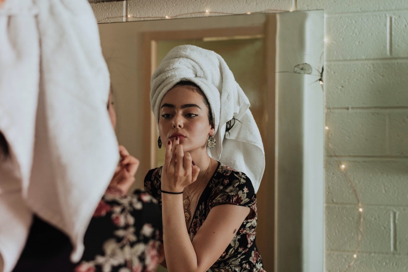 junge Frau behandelt ihre Gesichtshaut mit Calendulaöl Spiegelbild