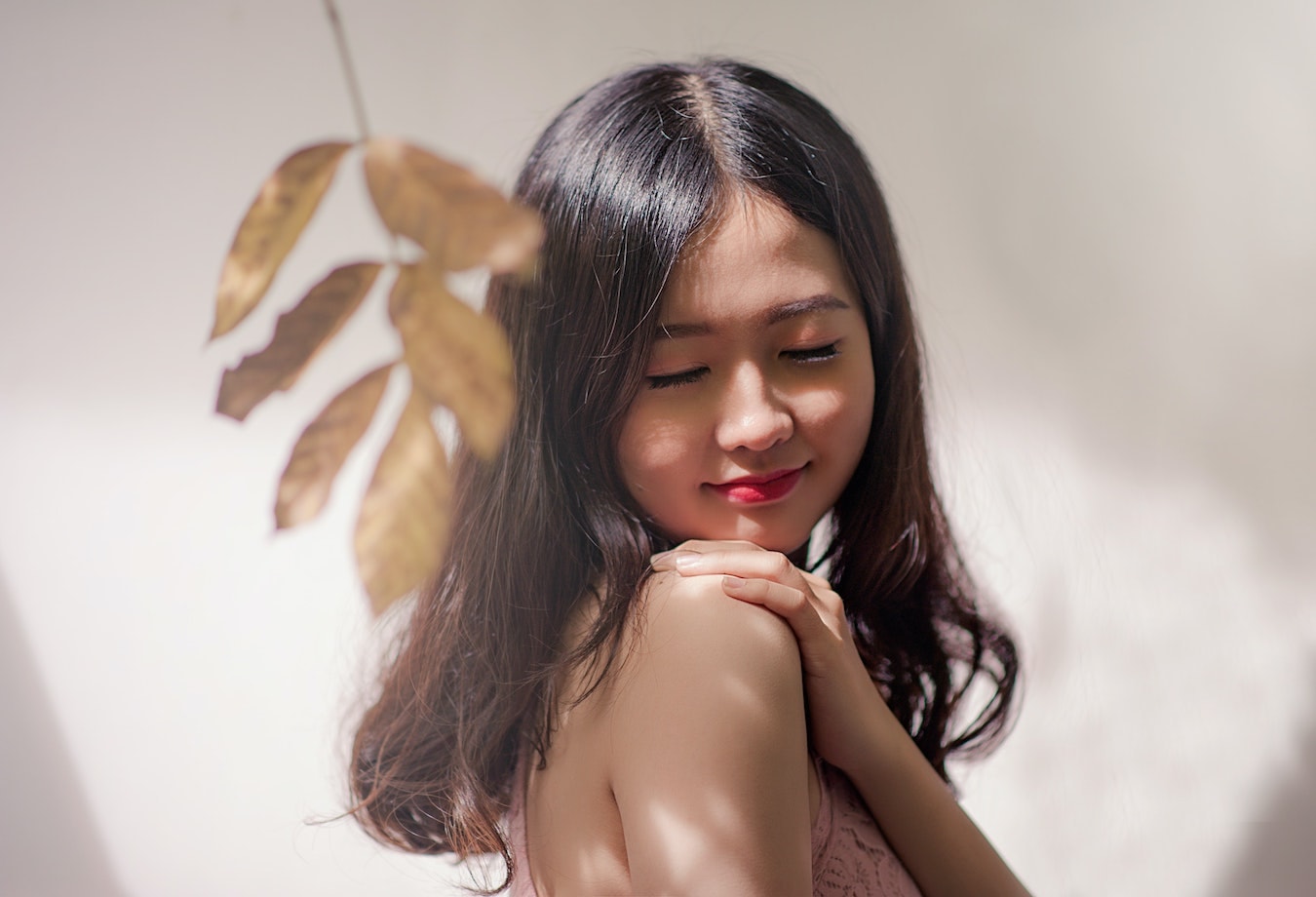junge asiatische Frau streicht sich über die Haut - natürliche Hautpflege, ätherische Öle für die Haut
