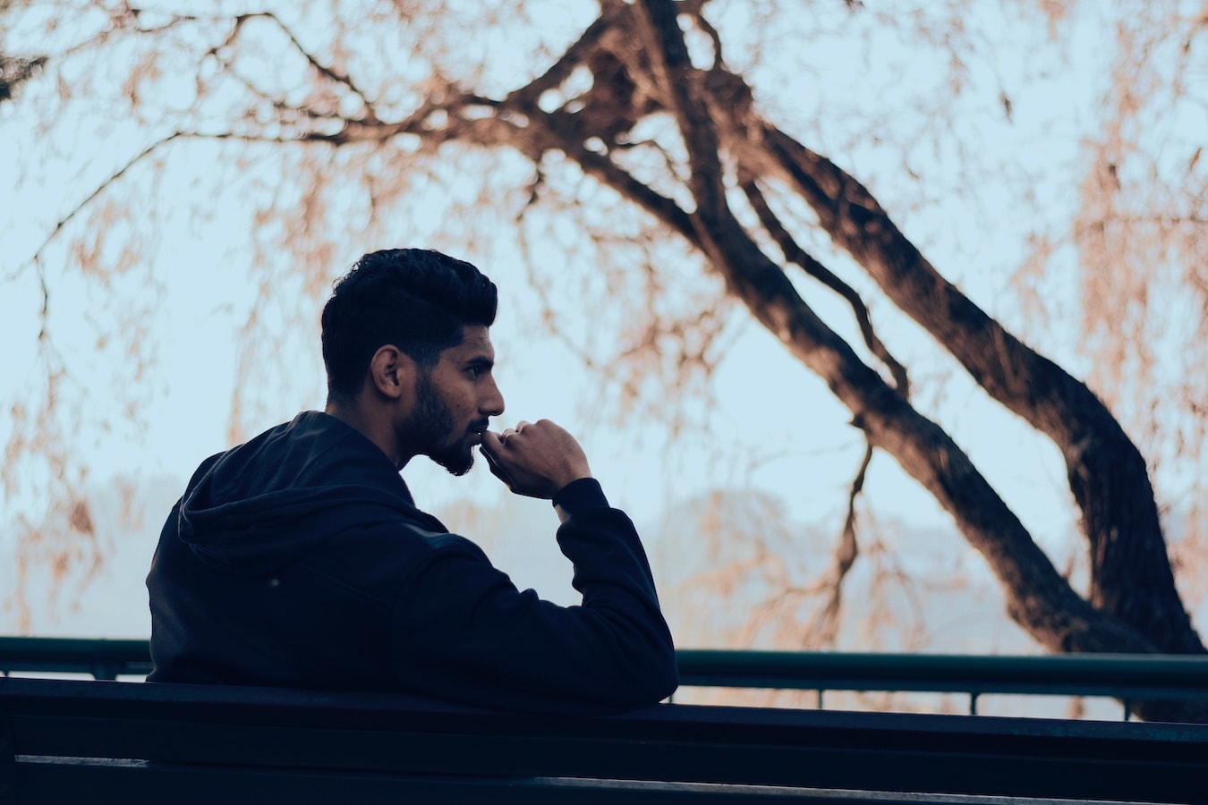 junger Mann sitzt im Park und denkt über seine Glaubenssätze nach