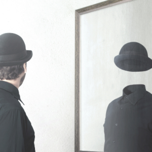 innere Leere - Mann in schwarz mit Hut sieht sich leer im Spiegel
