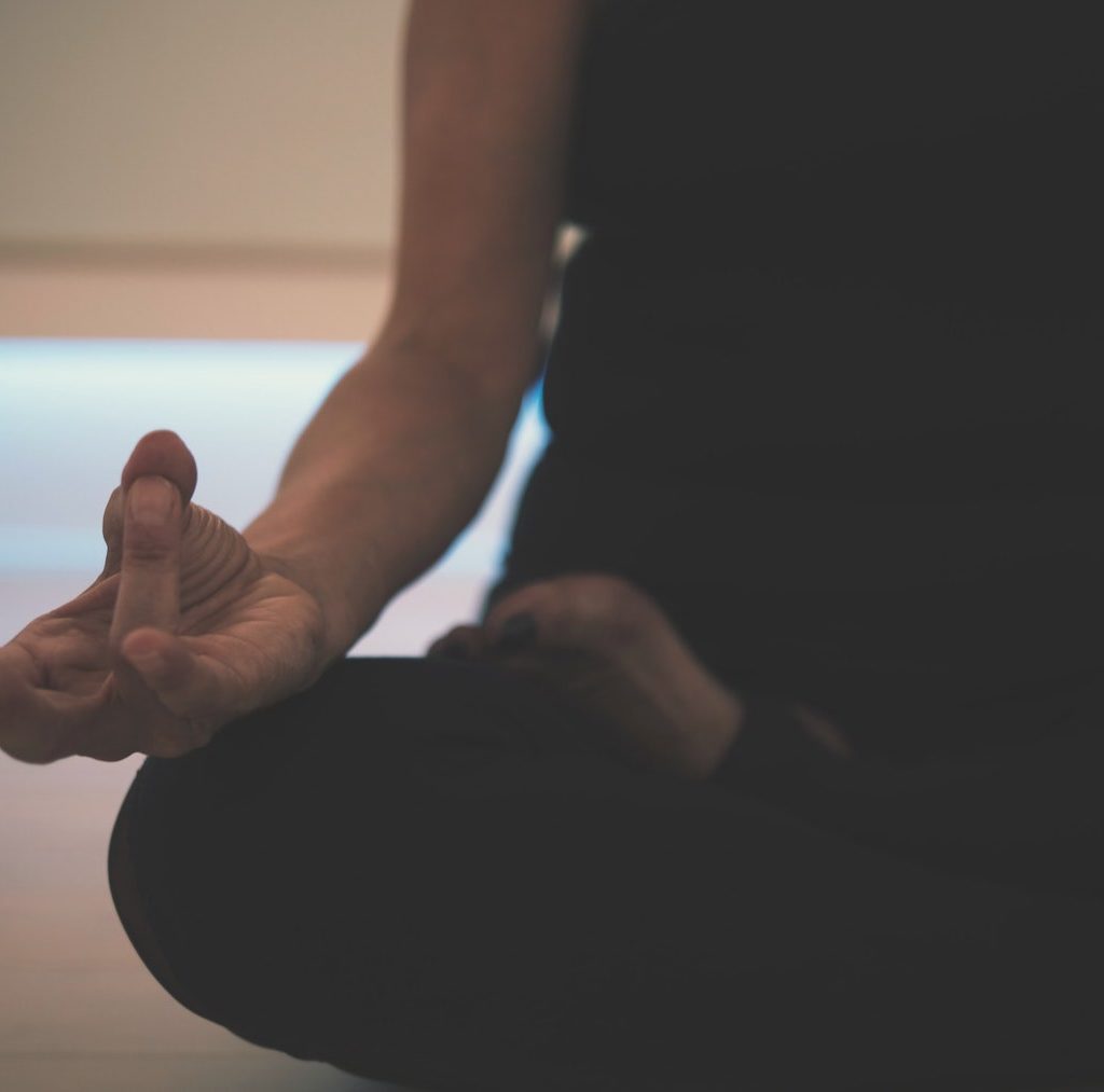 junge Frau sitzt auf dem Bett und meditiert - Meditation hilft die Innere Leere zu füllen