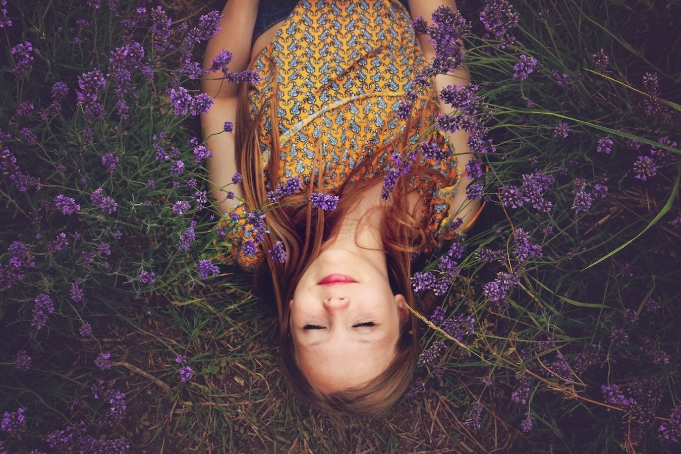 junge Frau liegt entspannt in einem Lavendelfeld