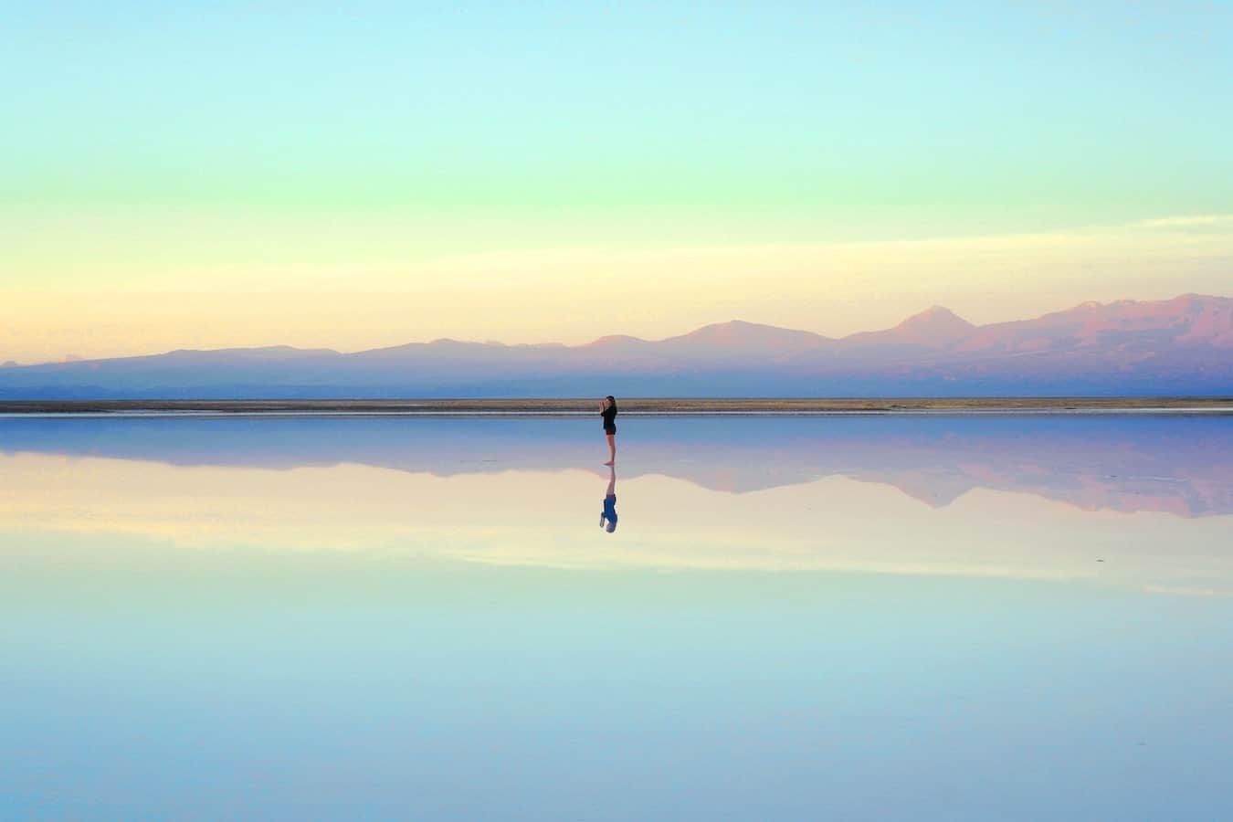 junge Frau läuft am Strand und reflektiert sich selbst im Wasser