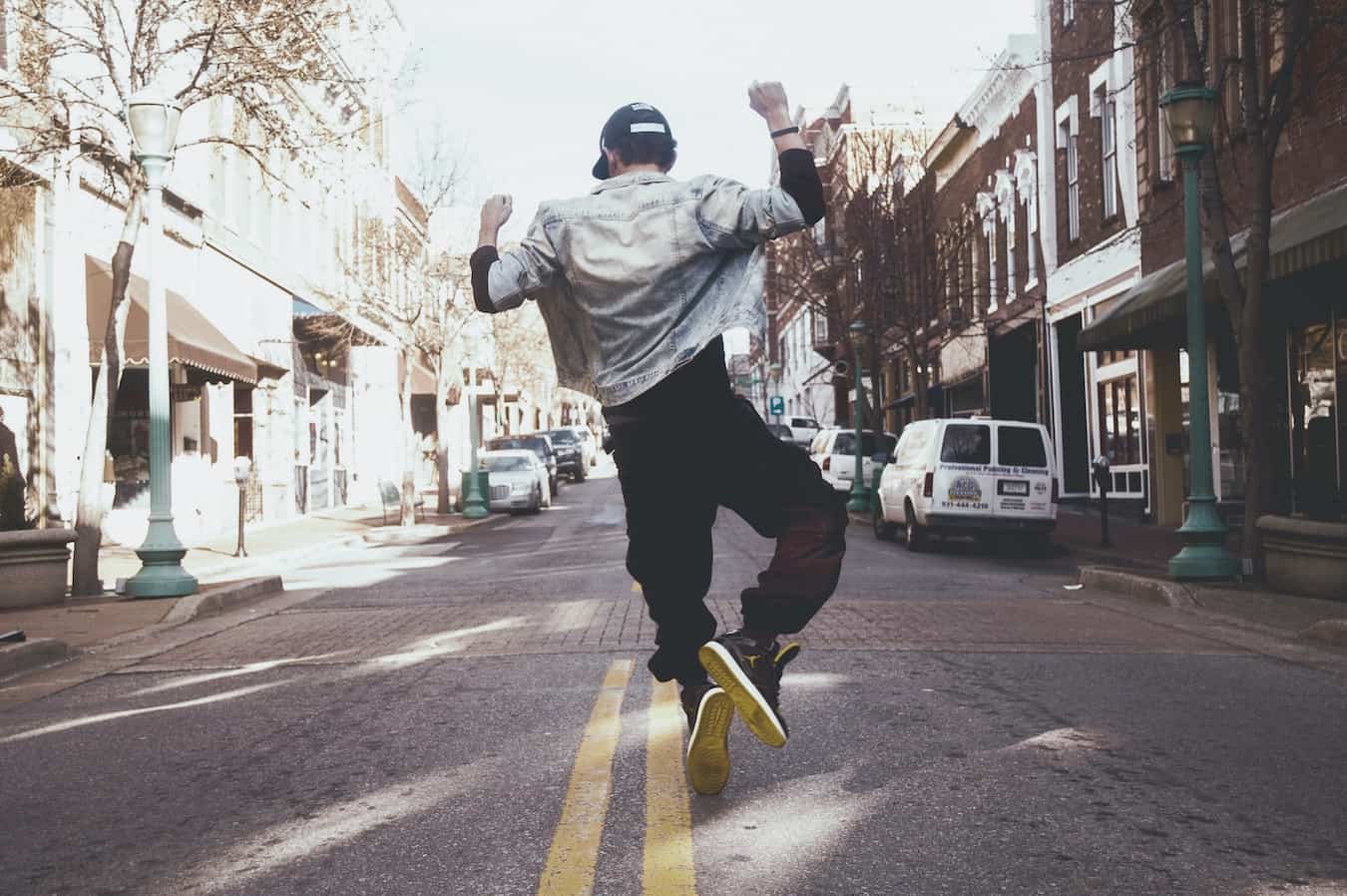 Junger Mann springt vor Freude auf der Straße