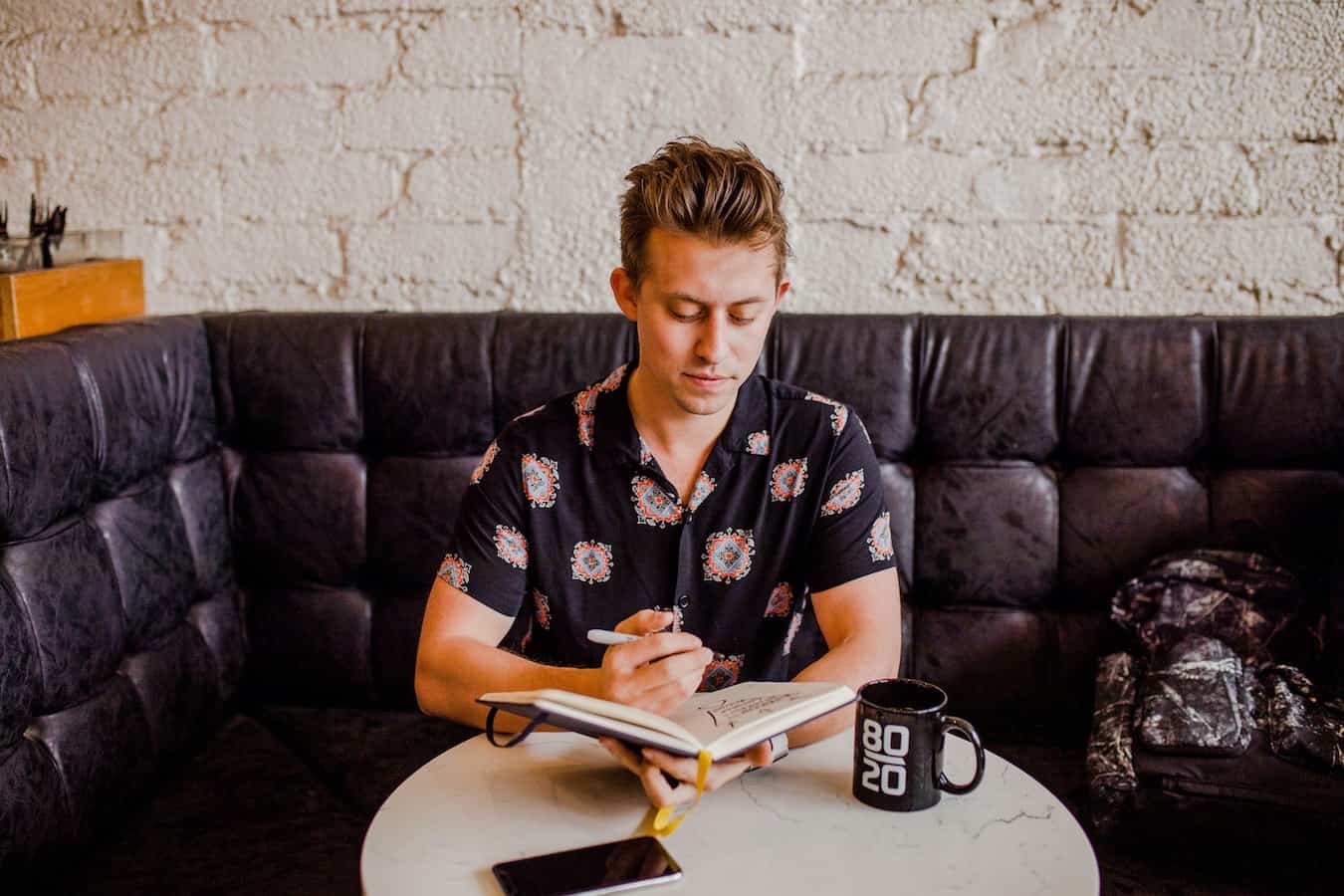 Junger Mann betreibt Journaling im Cafe