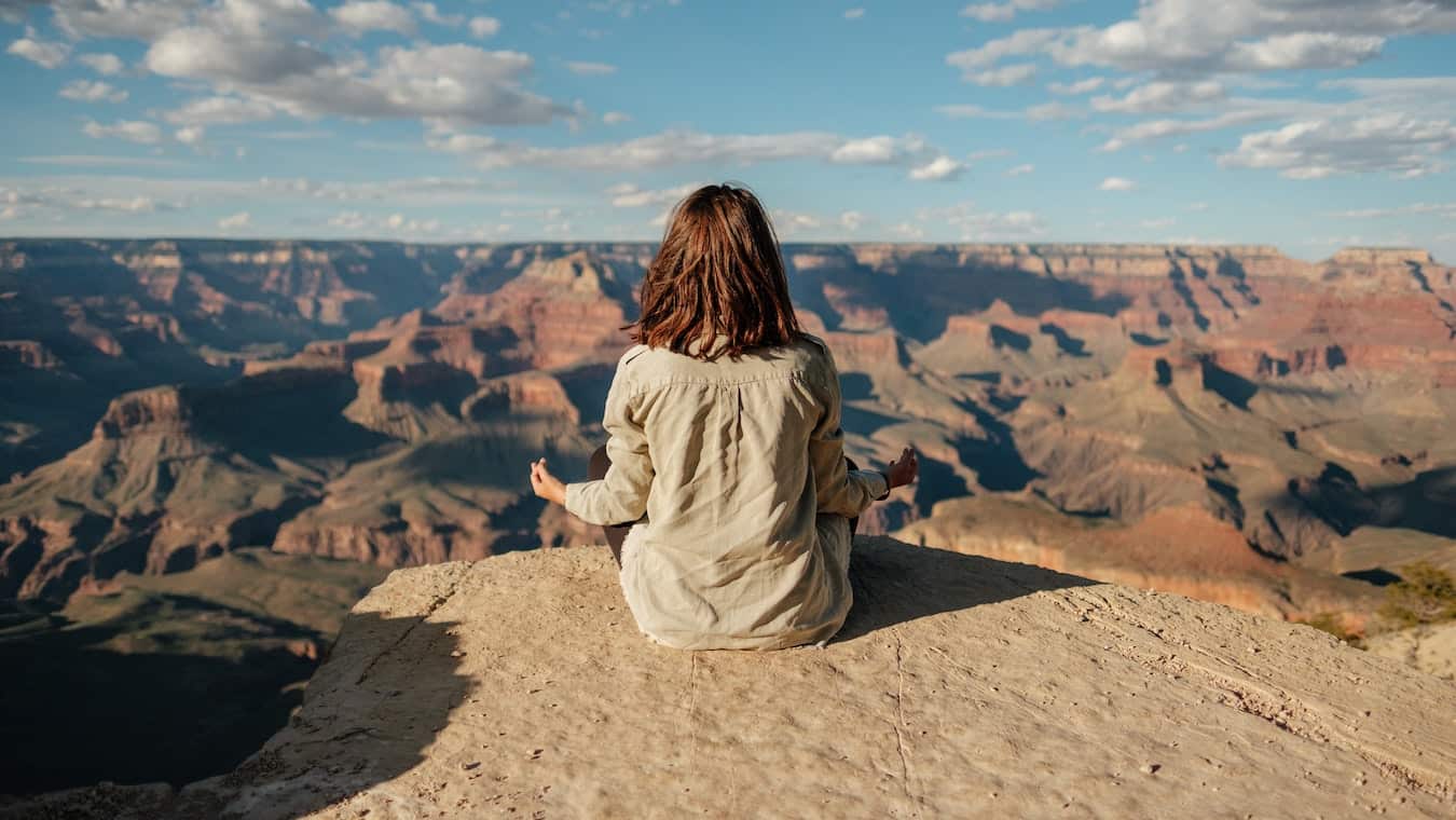 junge Frau sitzt an einem Felsen und Meditiert