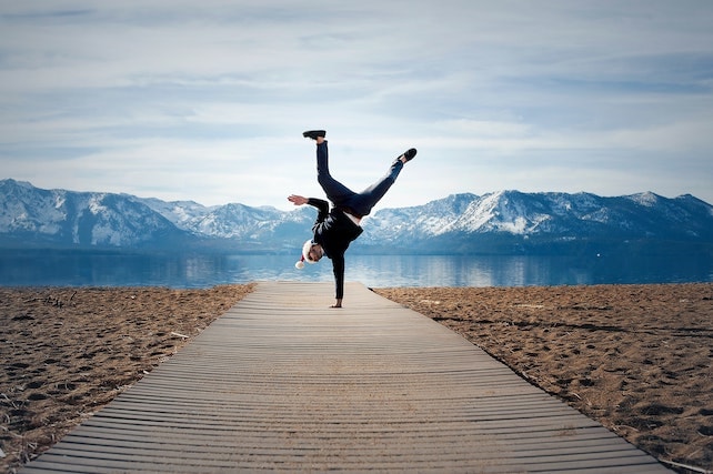 junger Mann macht mit Selbstsicherheit und einer positiven Einstellung einen Handstand vor einem See