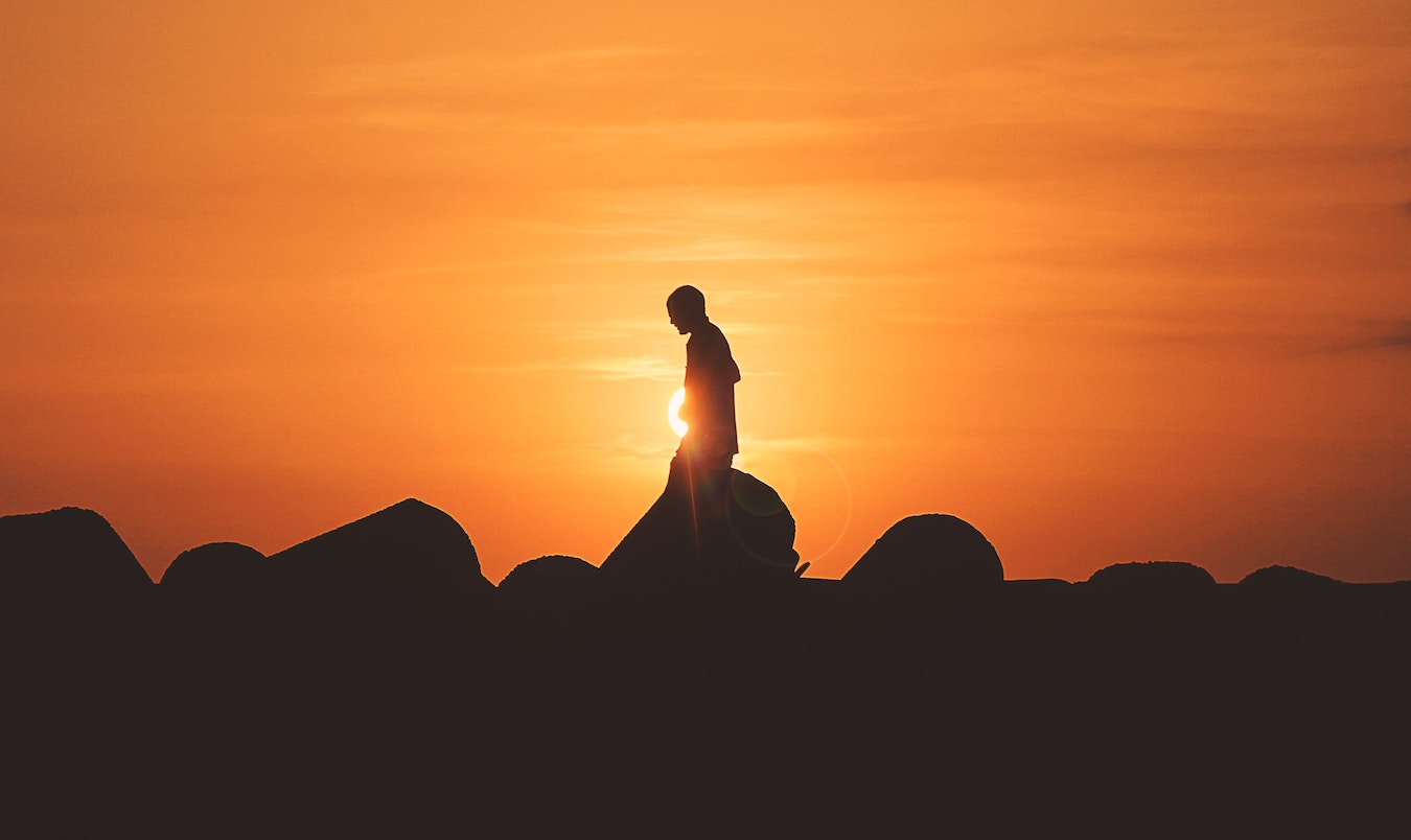 Schatten eines jungen Menschen mit sich selbst beschäftigt vor dem gelben Sonnenuntergang