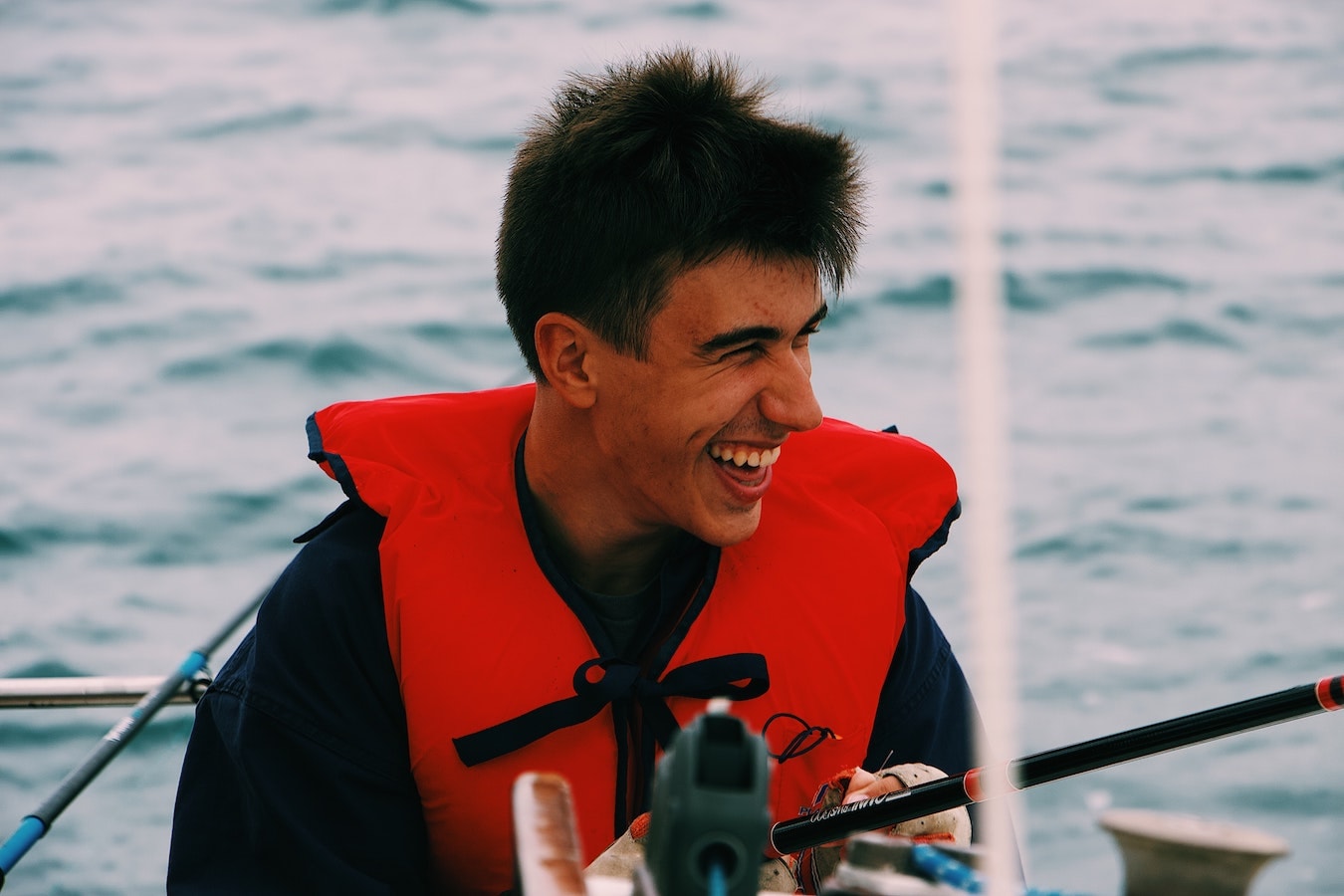 junger Mann lächelt auf einem Boot gute Laune positive Gedanken stärken die Selbstheilung
