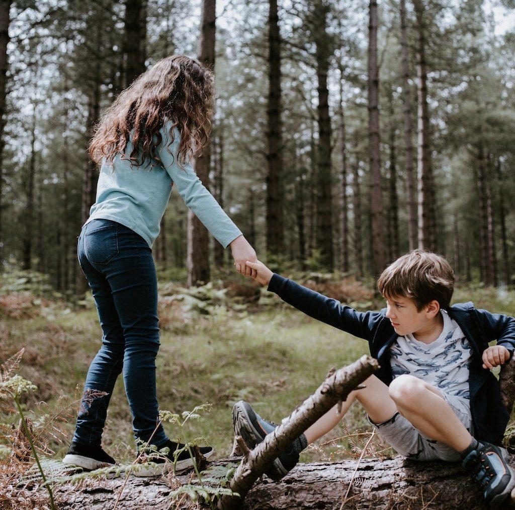 kleines Mädchen hilft einem kleinen Jungen vom Boden aufzustehen